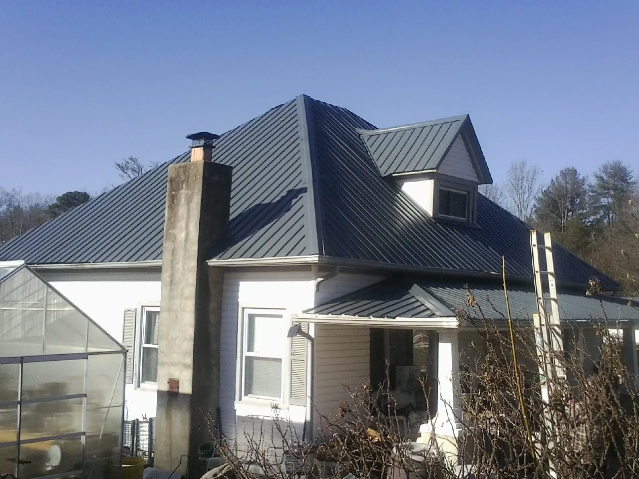 Dark blue standing seam metal roof on a white farmhouse with dormer — Slate & Tile Roof Repair by Roofing Brothers in Otisville