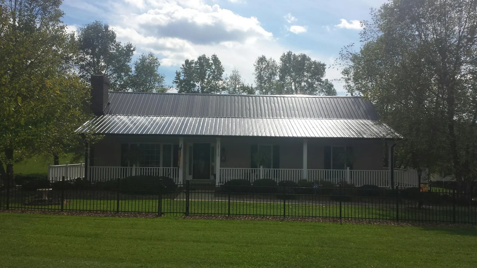 Gray metal roof on a brick ranch with a full width front porch — Gutter Guard Installation work by our crew in Otisville