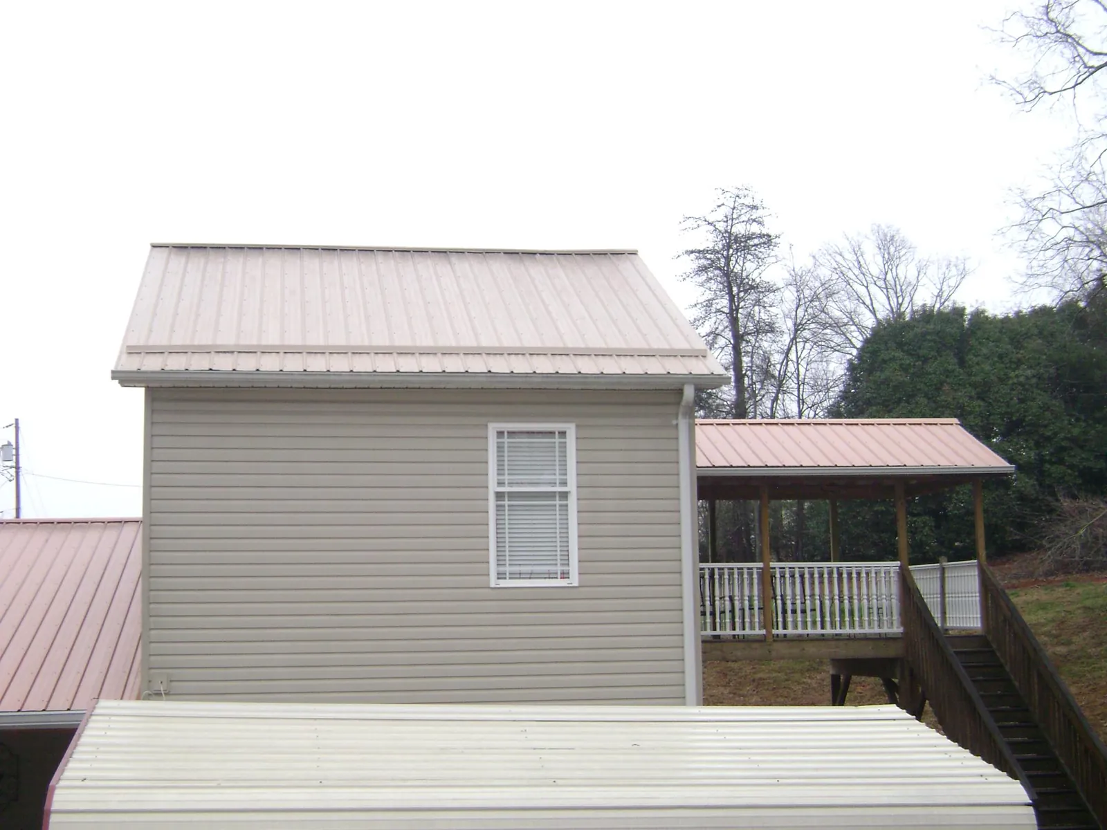 Tan metal roofs on a two story addition and attached porch, from a Roof Replacement job in Otisville